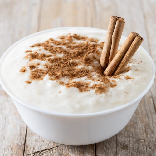 Arroz con leche. Rice pudding with cinnamon in bowl on wooden ta Arroz con leche. Rice pudding with cinnamon in bowl on wooden table